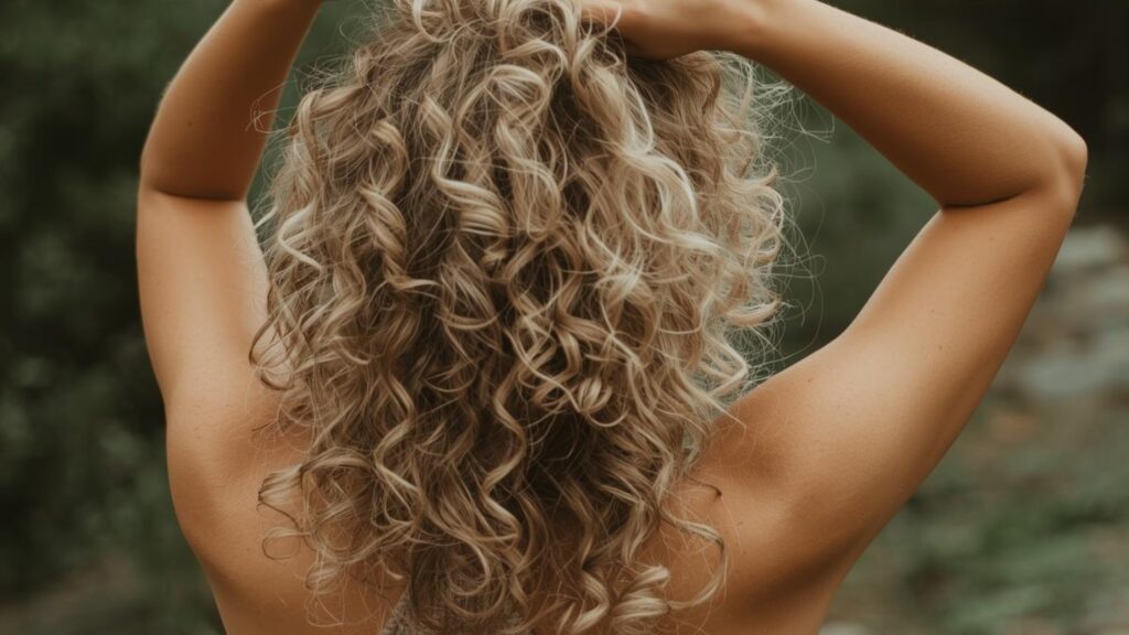 Mulher usando ativador de cachos natural no cabelo cacheado