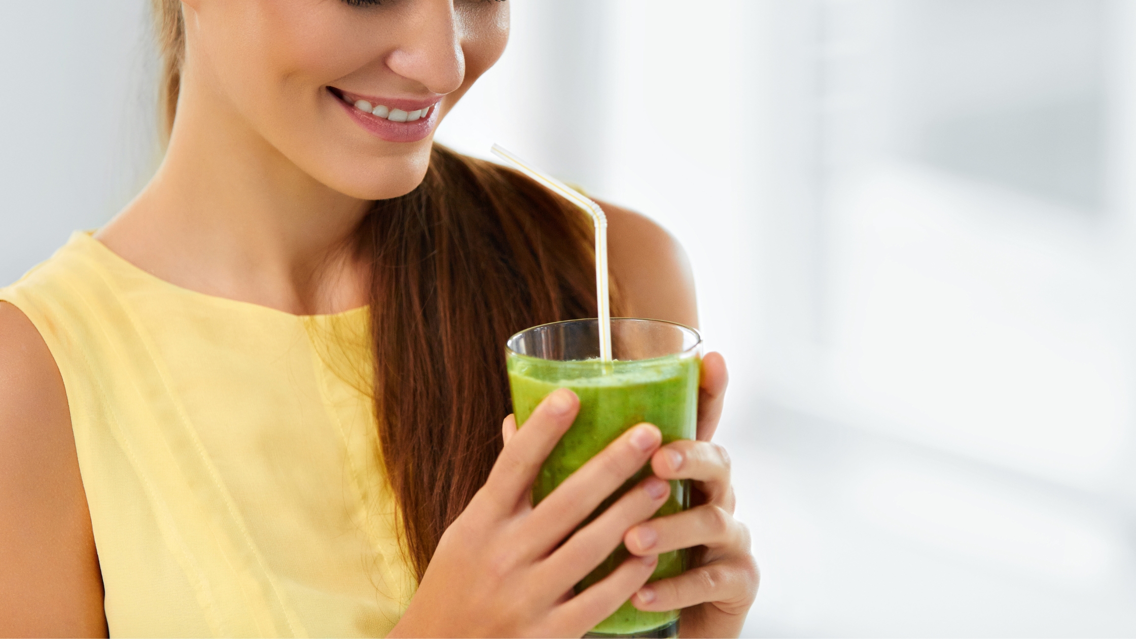 Mulher segurando copo com suco de couve